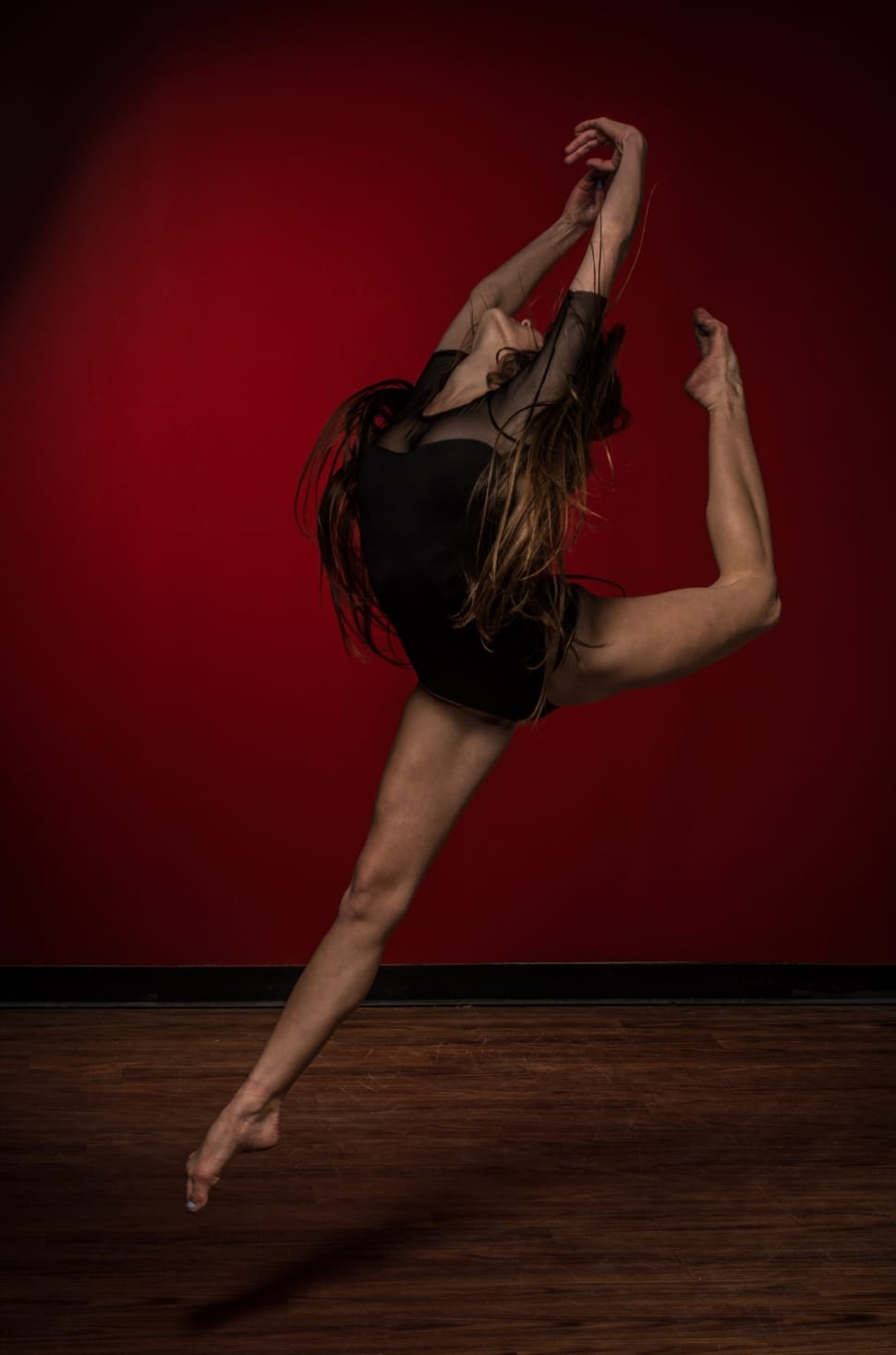 Brunette Haired Woman In Black Leotard Dancing Ballet Against Red