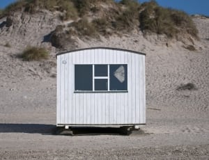 white wooden shed on a gray sandy plateau thumbnail