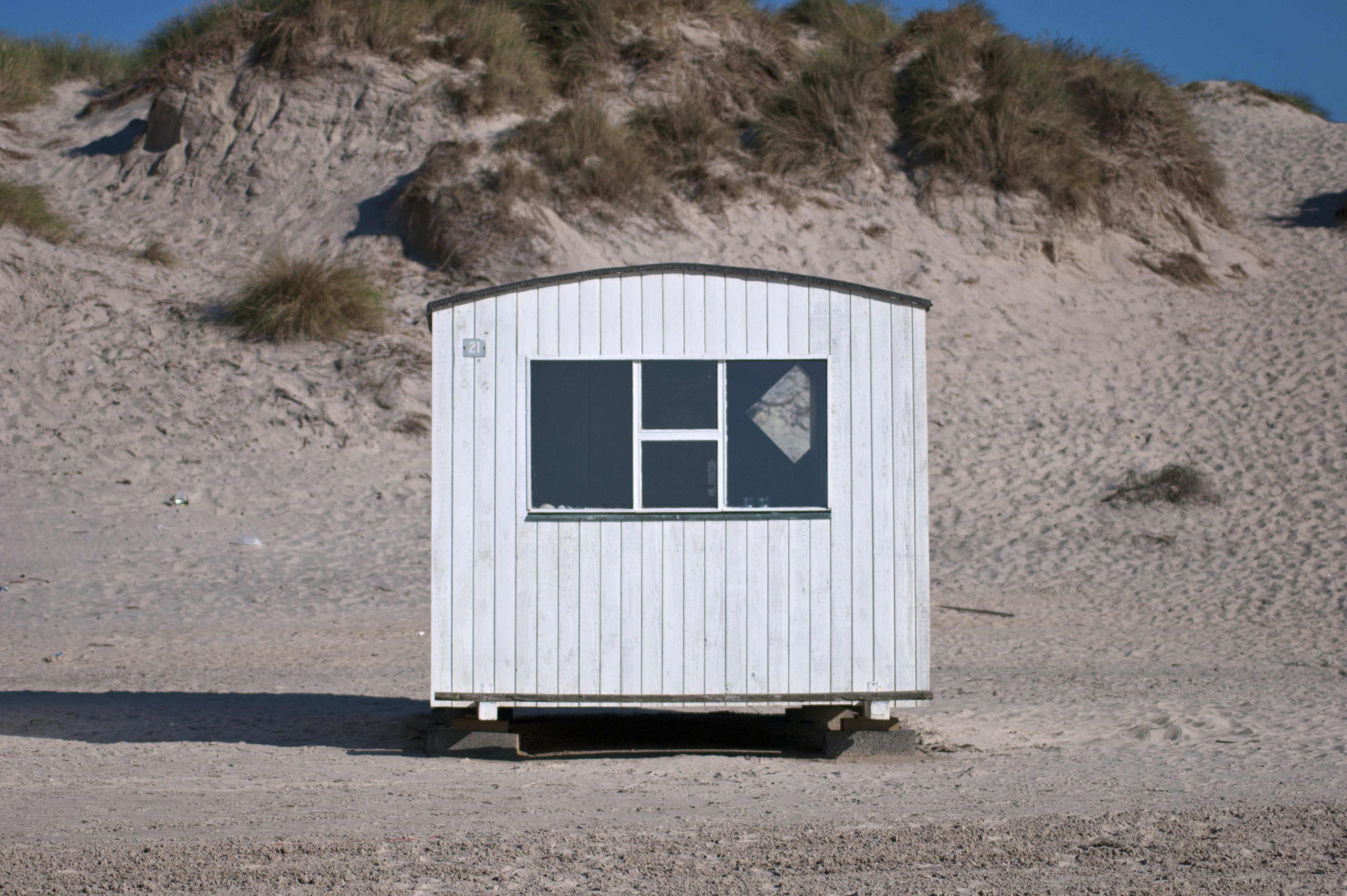 white wooden shed on a gray sandy plateau