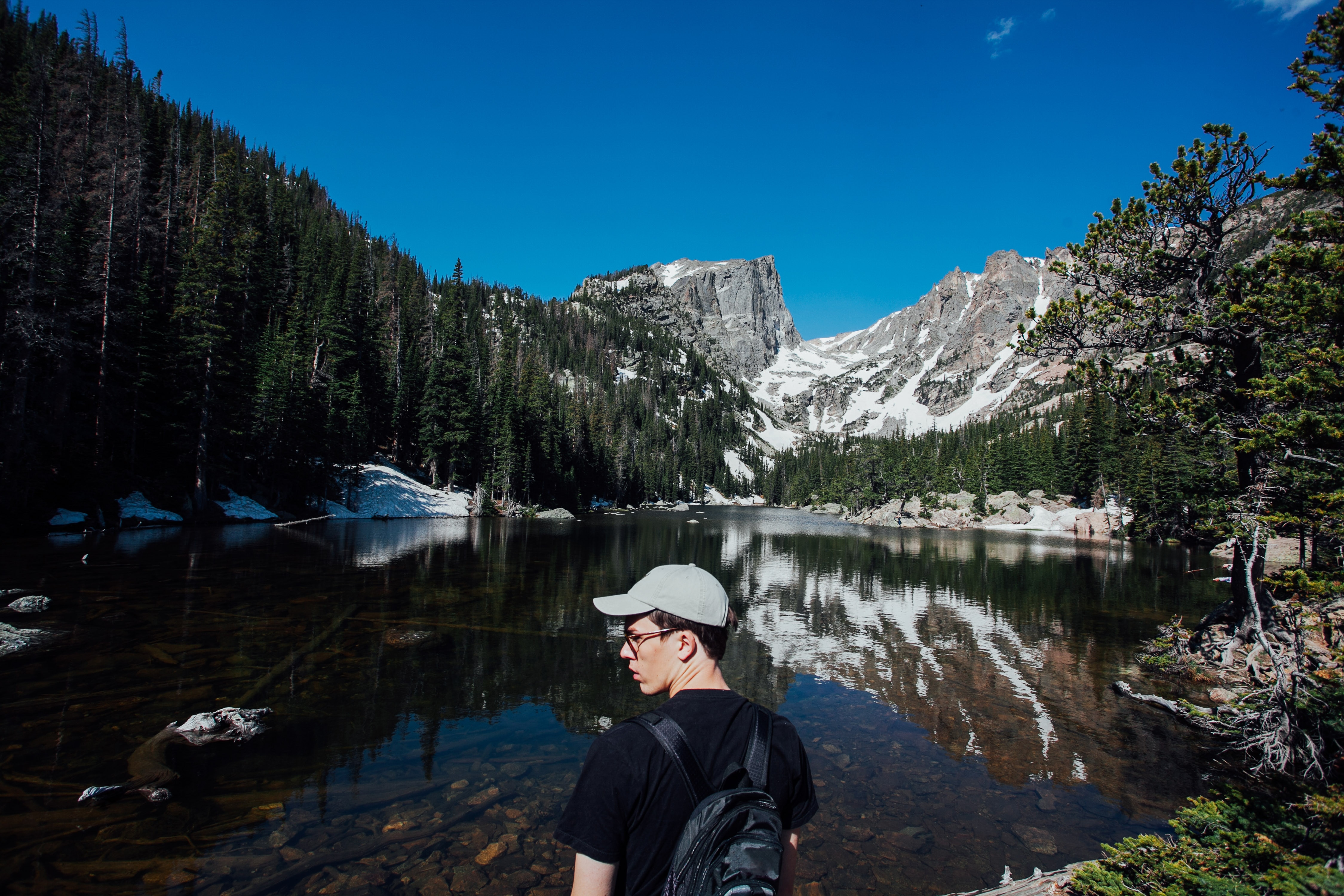 man wearing black t-shirt looking at lake during day time