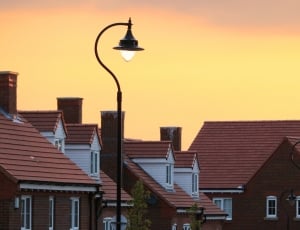 black steel street light front of maroon houses during sunset time thumbnail