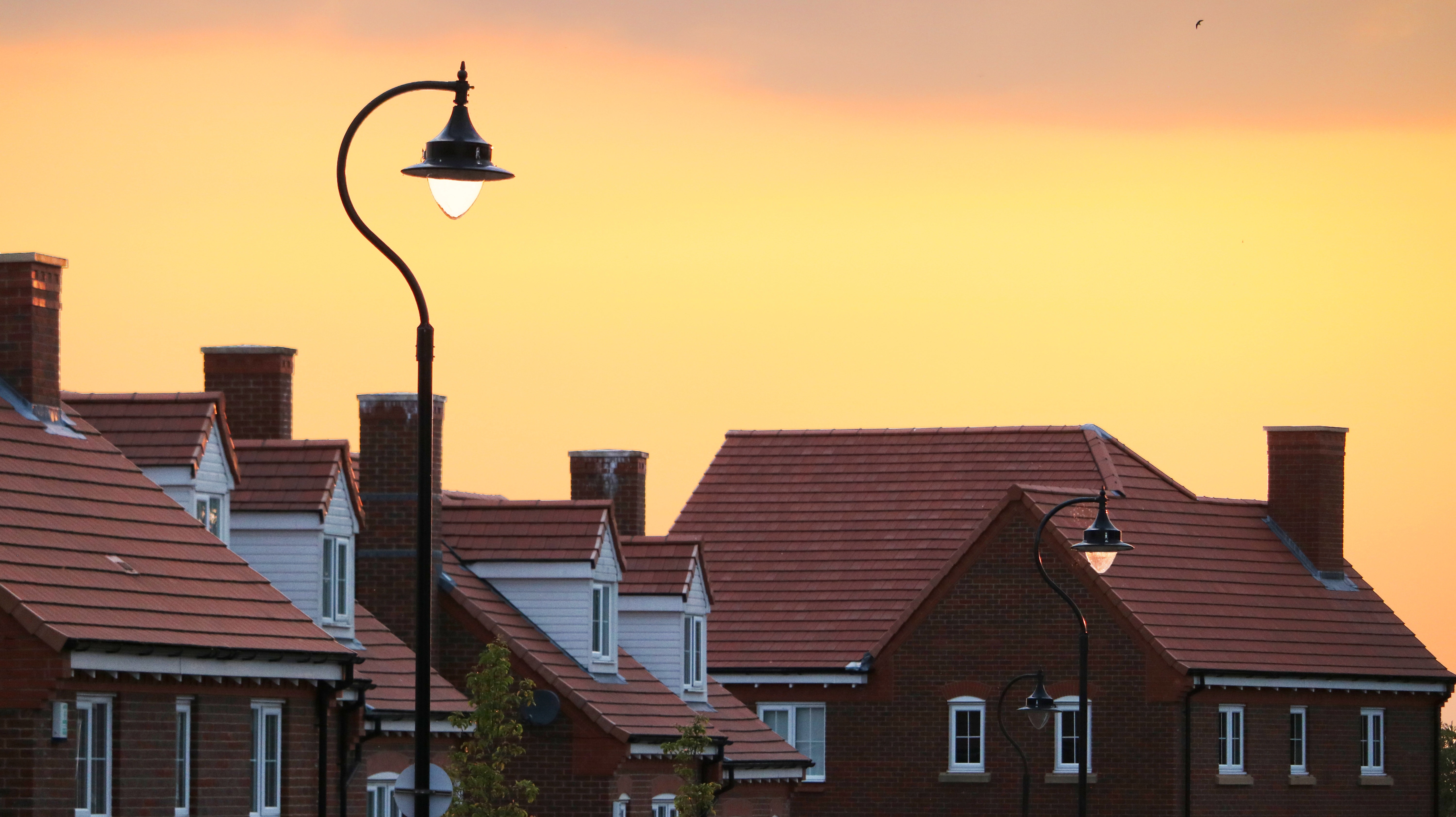 black steel street light front of maroon houses during sunset time