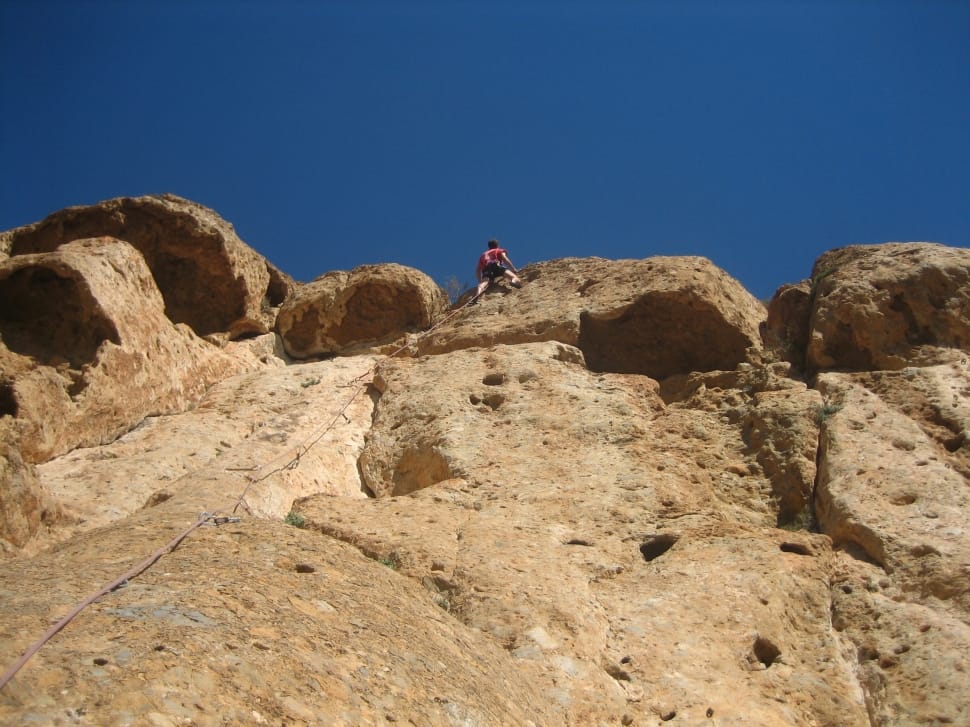 person climbing rock cliff during daytime preview