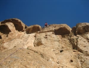 person climbing rock cliff during daytime thumbnail