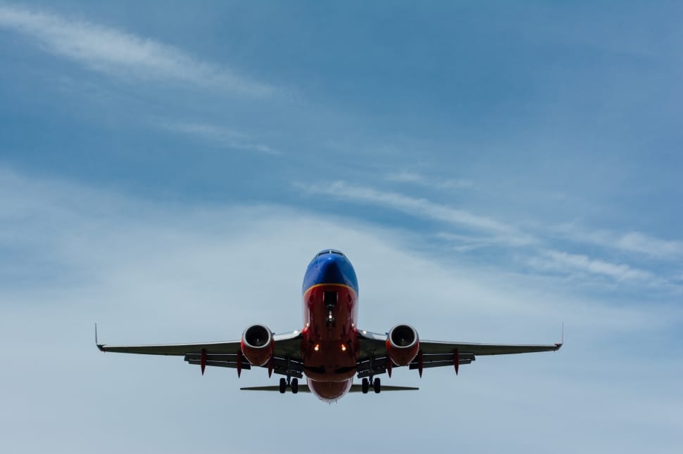 red and blue airplane on blue sky and white clouds preview