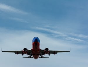 red and blue airplane on blue sky and white clouds thumbnail
