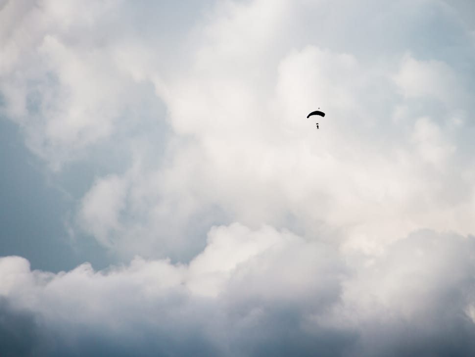 person on parachute under white clouds during daytime preview
