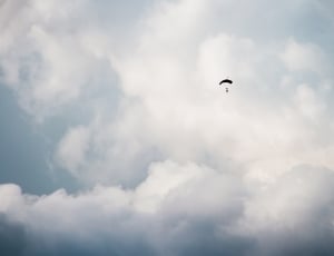 person on parachute under white clouds during daytime thumbnail