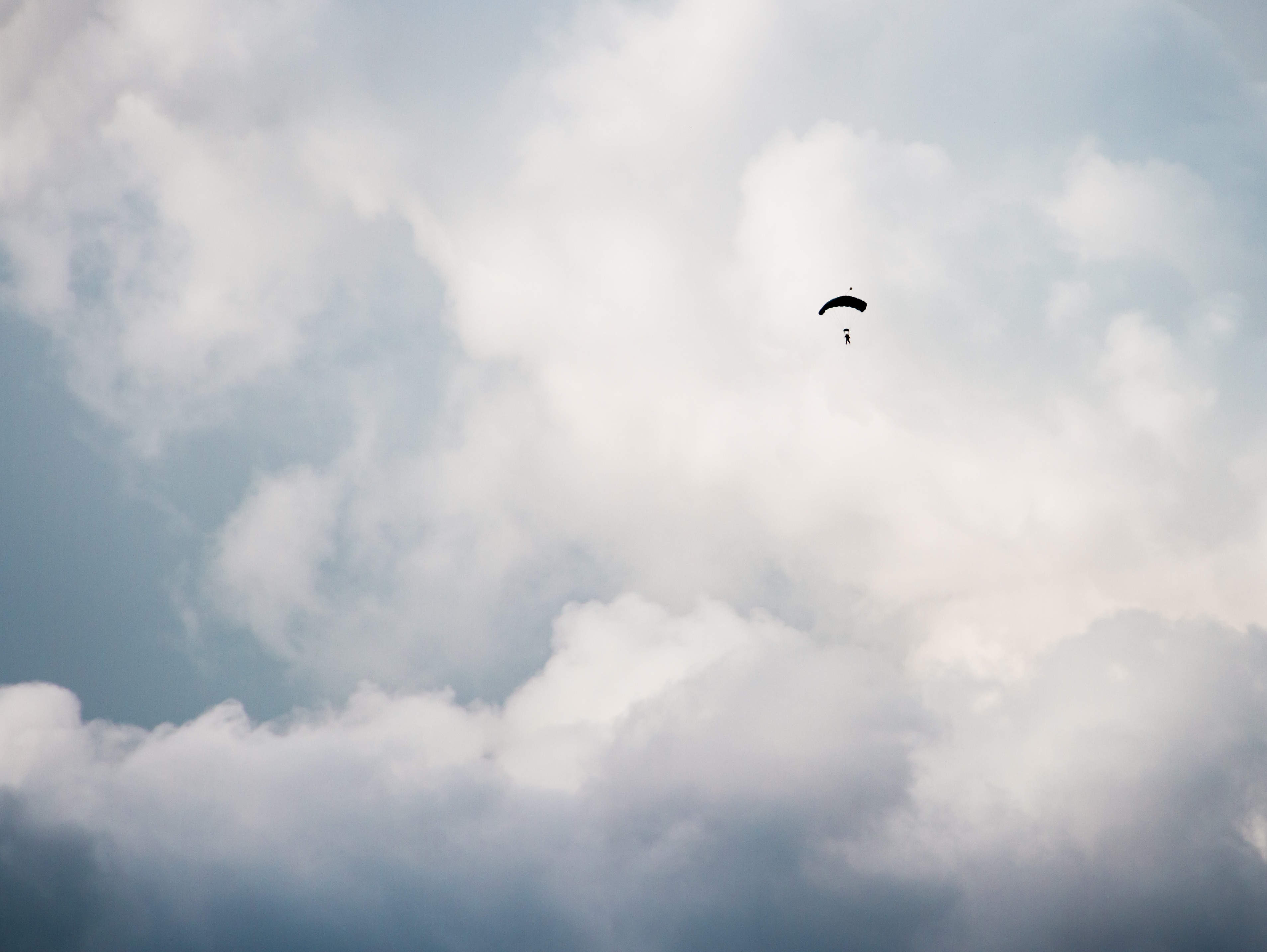 person on parachute under white clouds during daytime