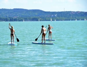 3 people standing on surf board thumbnail