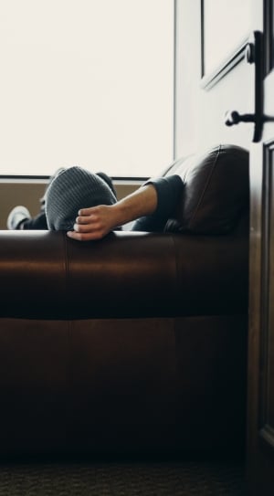 man lying on the couch by the window thumbnail