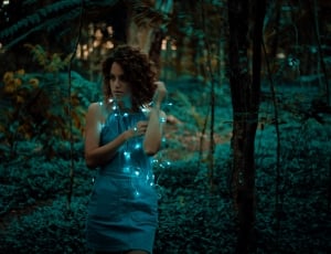 woman standing near forest with string lights on body thumbnail