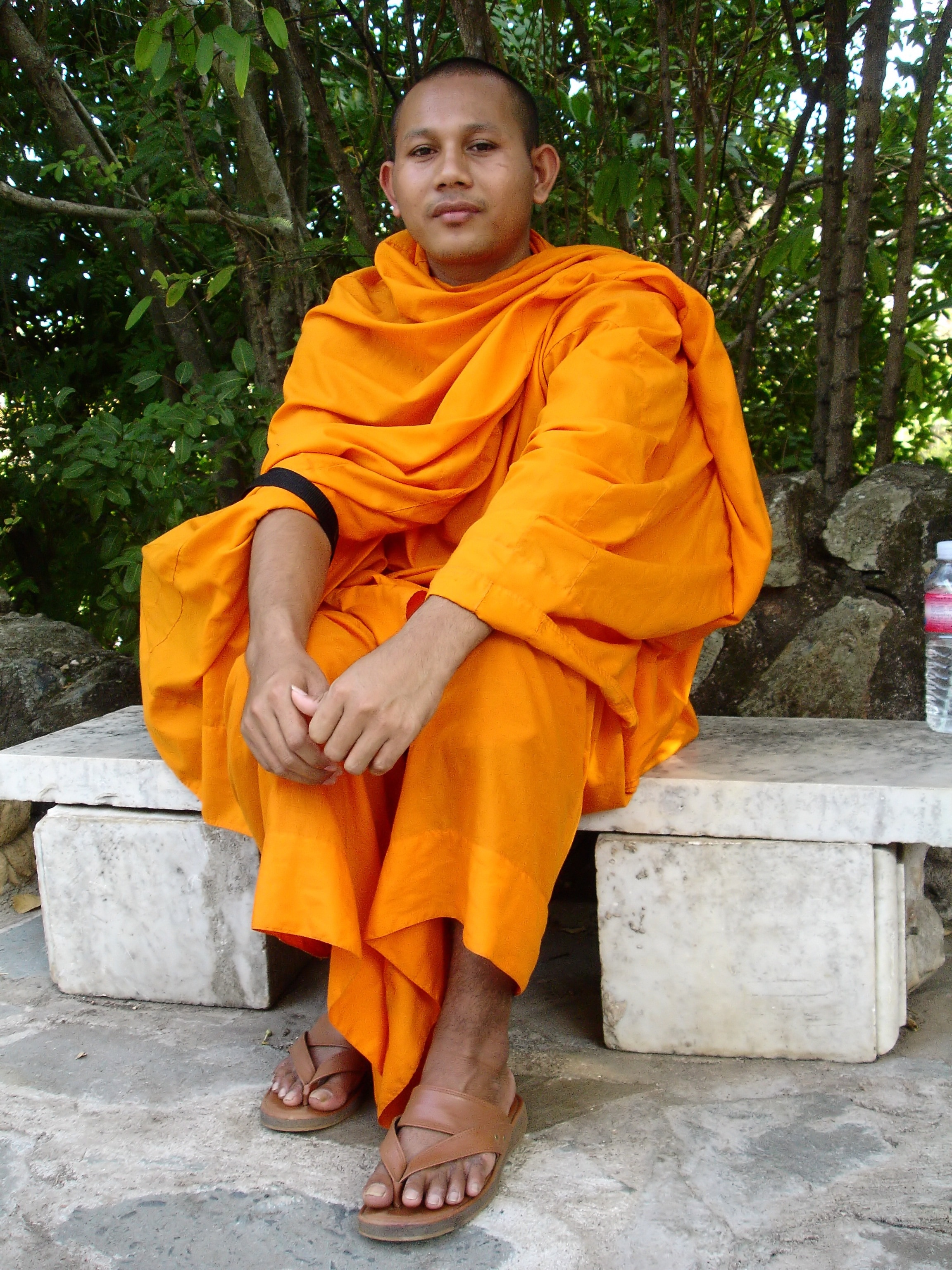man wearing orange robe sitting on bench