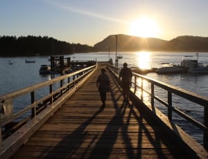 silhouette photo of 2 person walking on dock thumbnail
