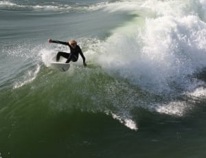 men's black wet suit and white surfboard thumbnail