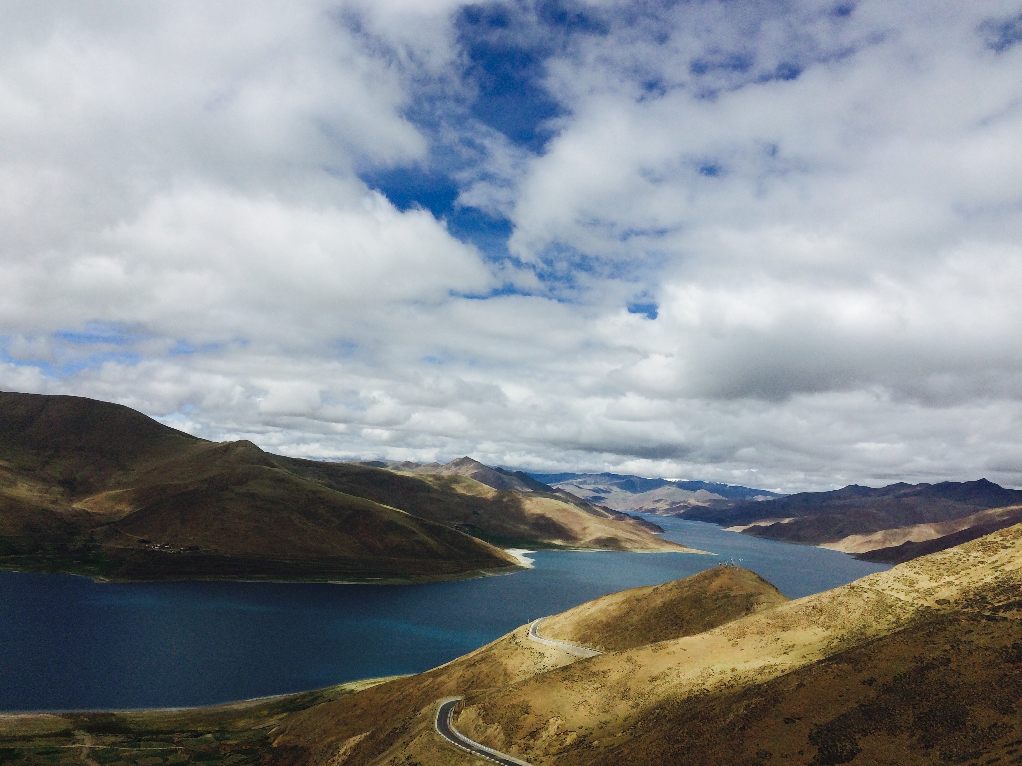 aerial view of brown mountains and body of water under cloudy sky