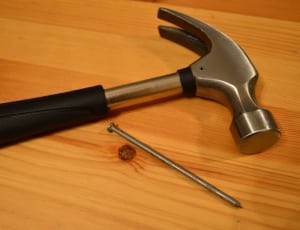 black handled claw hammer with nail thumbnail