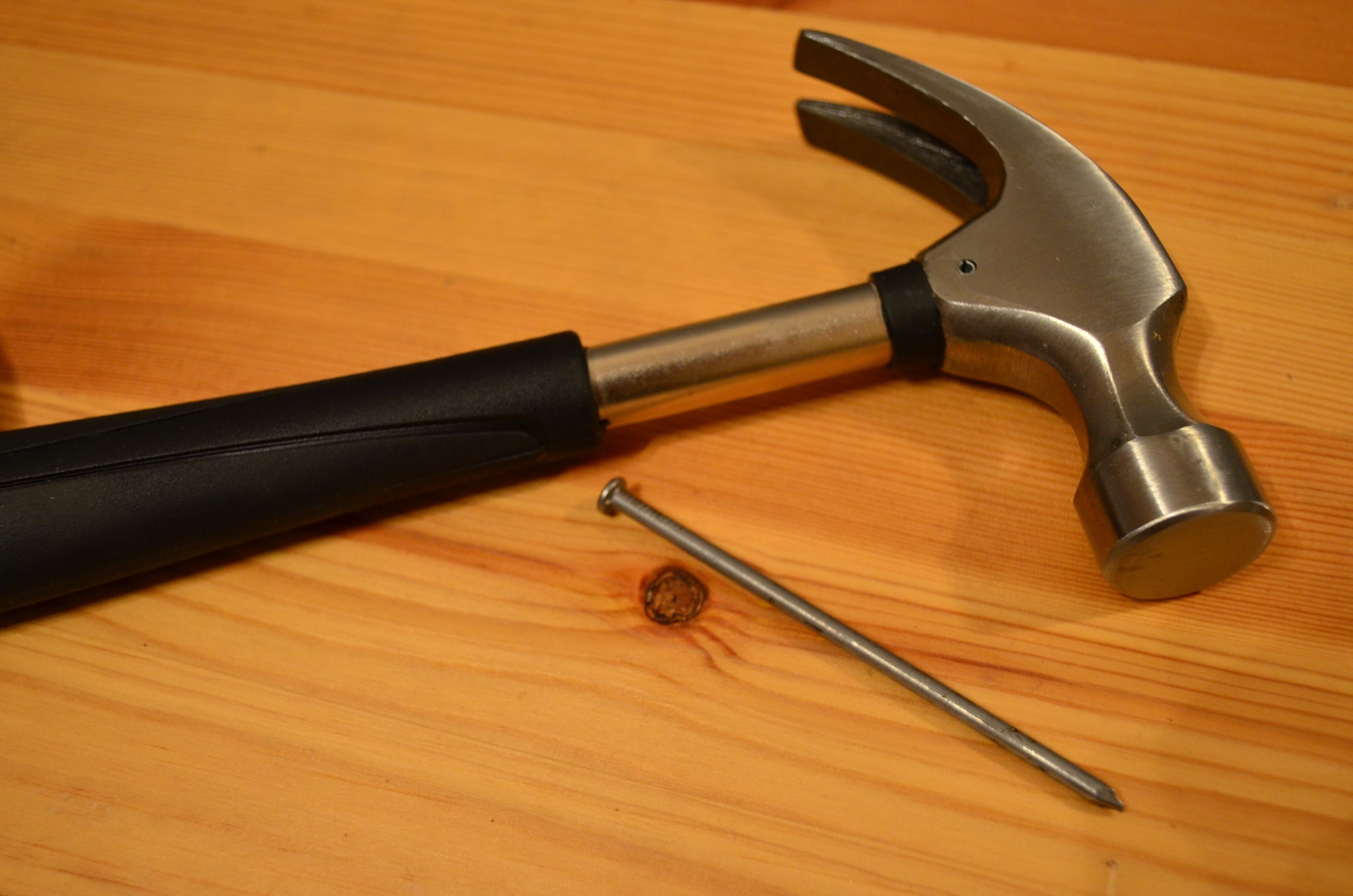 black handled claw hammer with nail