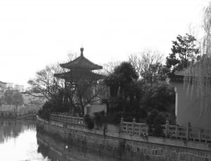 grayscale photo of pagoda beside body of water thumbnail