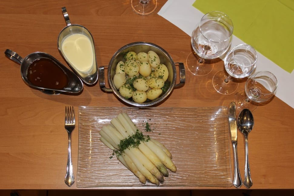 three clear wine glasses beside cook food in cooking pot and stainless steel sauce container on table preview