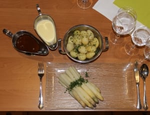 three clear wine glasses beside cook food in cooking pot and stainless steel sauce container on table thumbnail