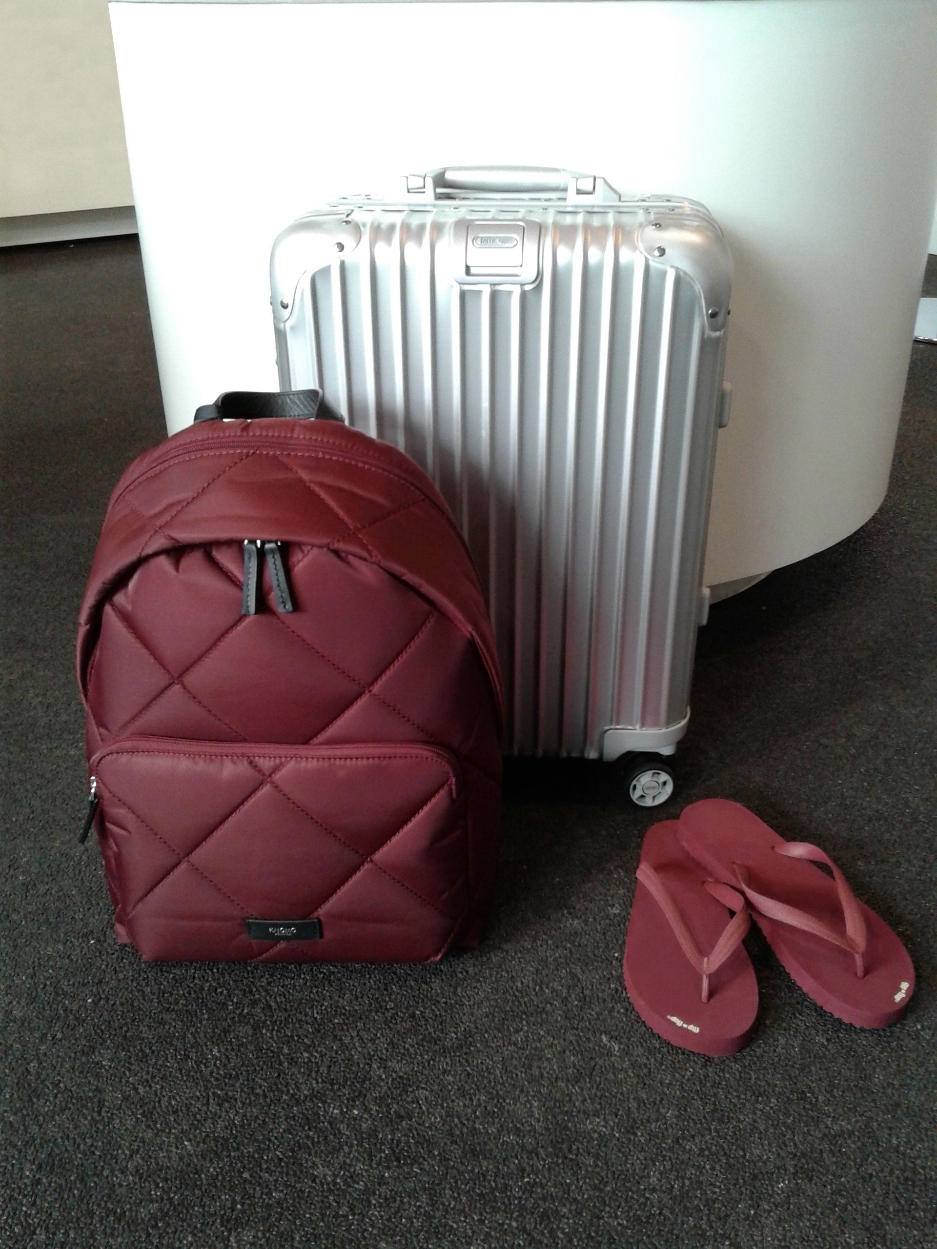 red backpack pair of red flip flops and silver luggage bag