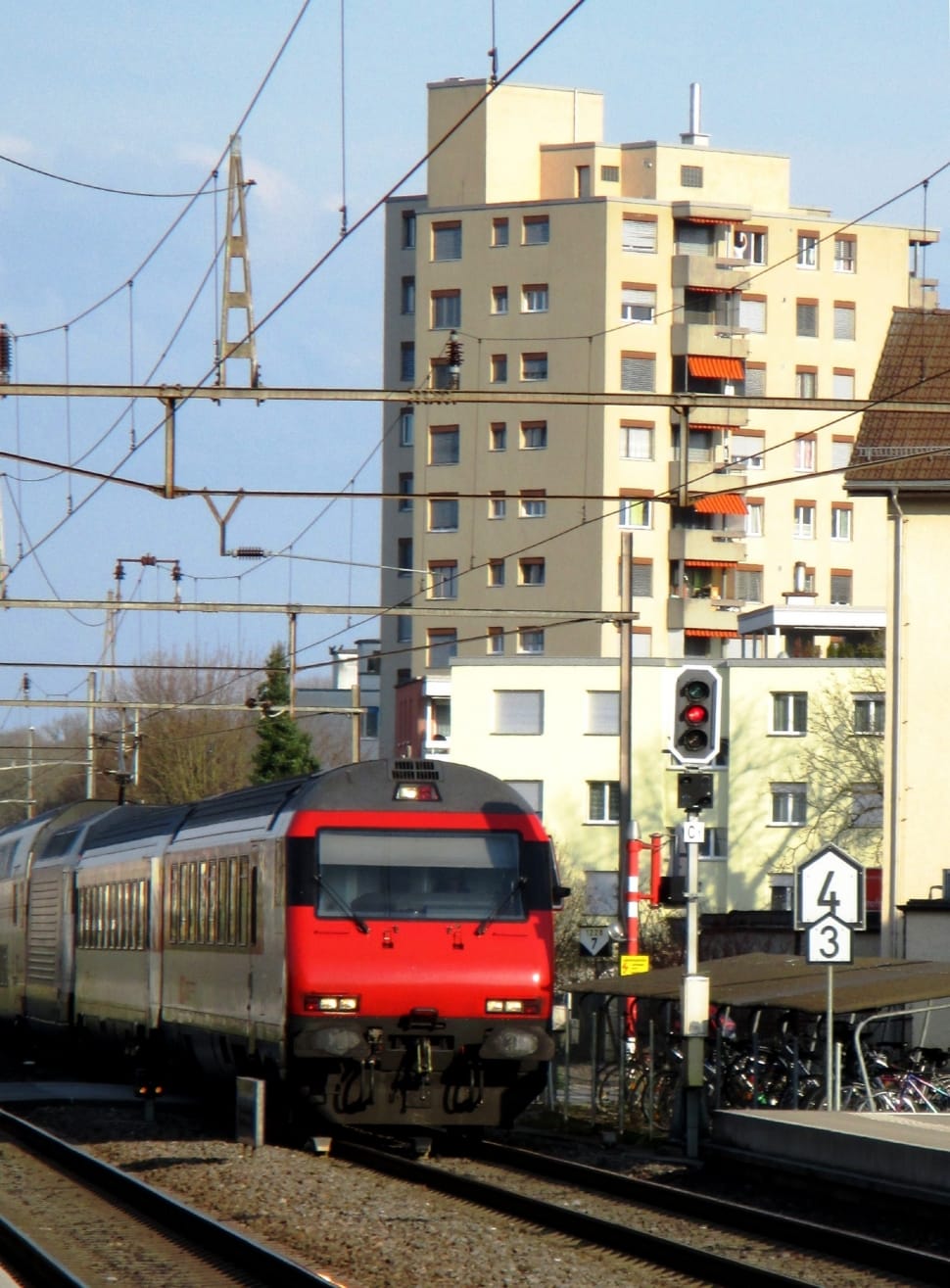 red and gray train passing white and black traffic light near station during daytime preview