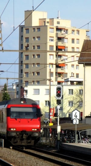 red and gray train passing white and black traffic light near station during daytime thumbnail