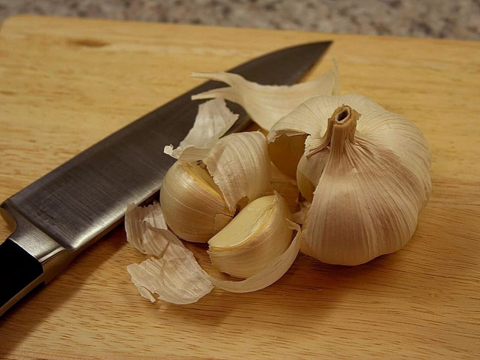 white garlic beside gray knife on brown surface preview