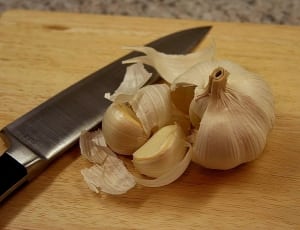 white garlic beside gray knife on brown surface thumbnail