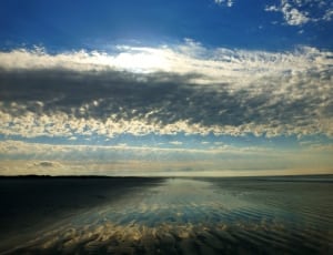 ocean under white clouds and blue sky thumbnail