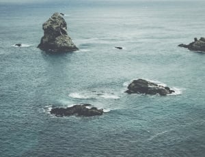 body of water and black rocks aerial photo thumbnail