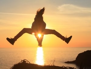 silhouette of person jumping on body of water against sunlight thumbnail