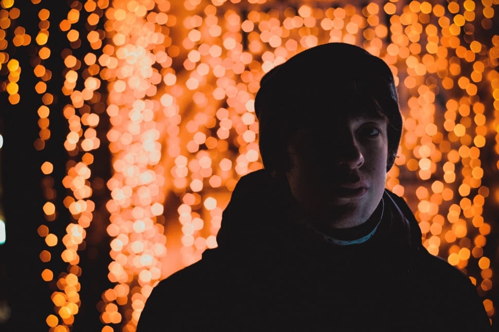 man in jacket with string lights as background preview
