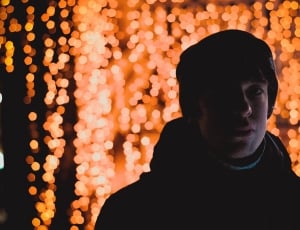 man in jacket with string lights as background thumbnail