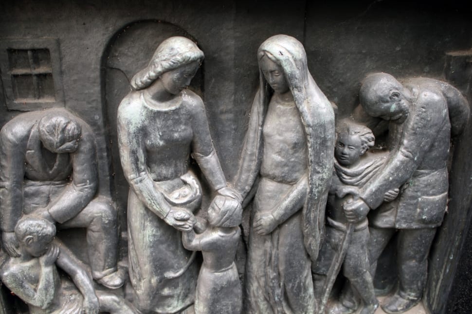 gray sculpture of 2 women tending to a girl preview