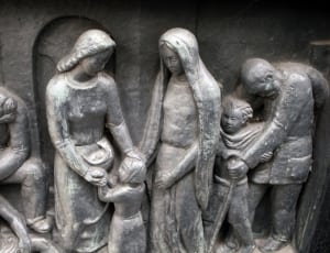 gray sculpture of 2 women tending to a girl thumbnail