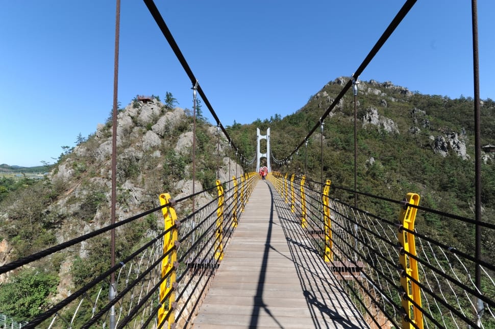 brown wooden hanging bridge near green rocky mountain preview