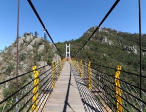 brown wooden hanging bridge near green rocky mountain thumbnail