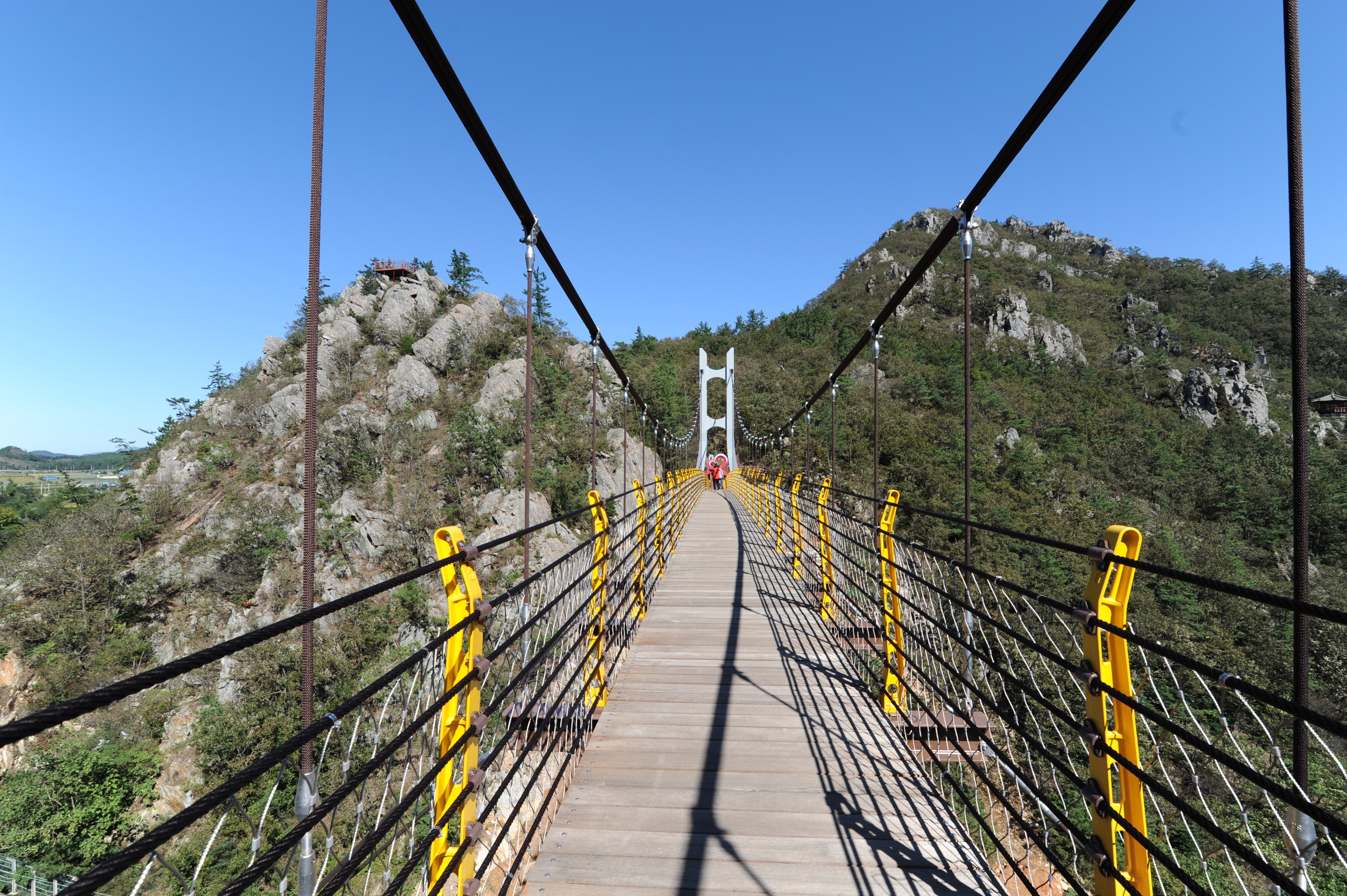 brown wooden hanging bridge near green rocky mountain
