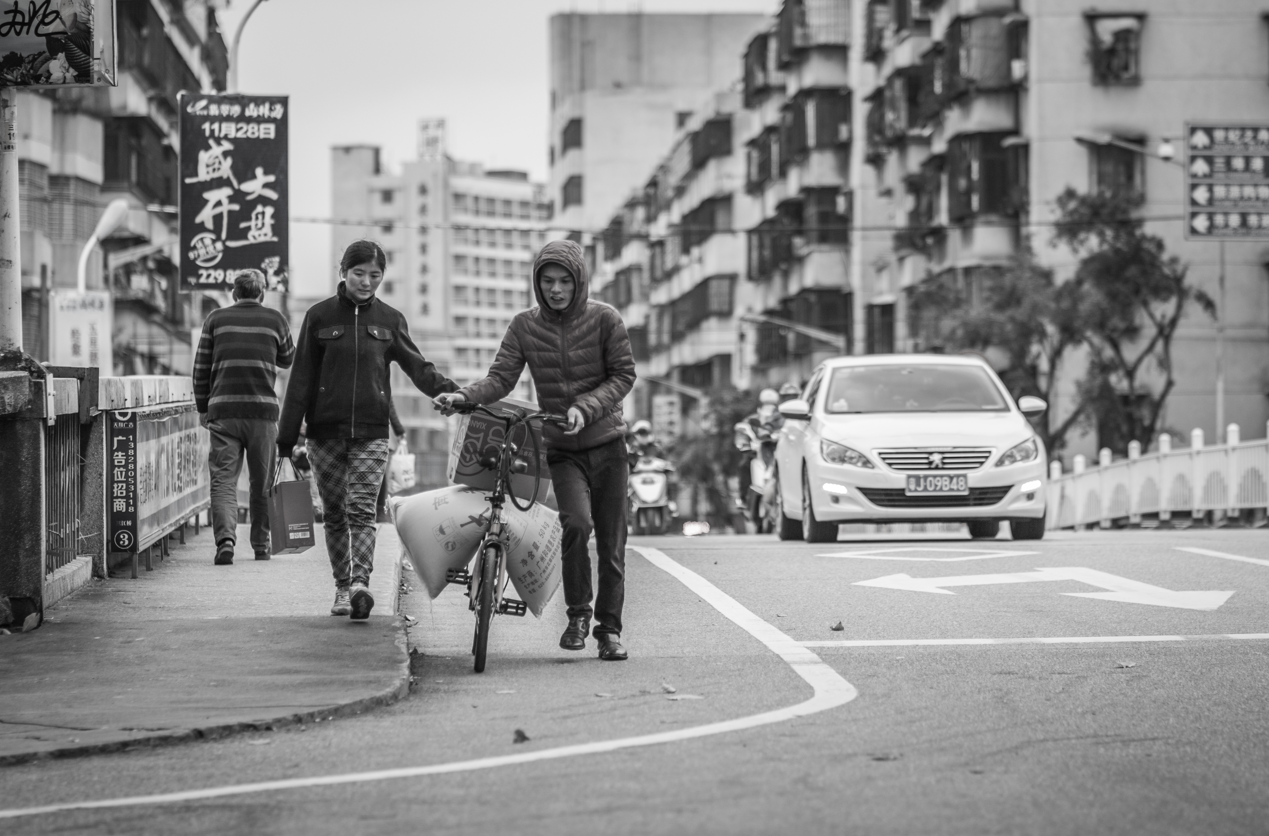 grayscale photo of man and woman pushing bicycle