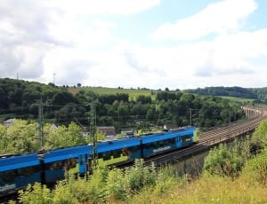 blue train on railway during daytime thumbnail