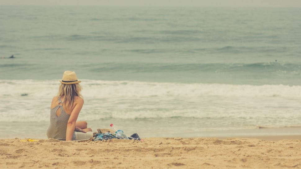 woman wearing hat and tank top sitting in beach preview