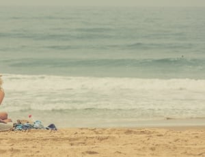 woman wearing hat and tank top sitting in beach thumbnail