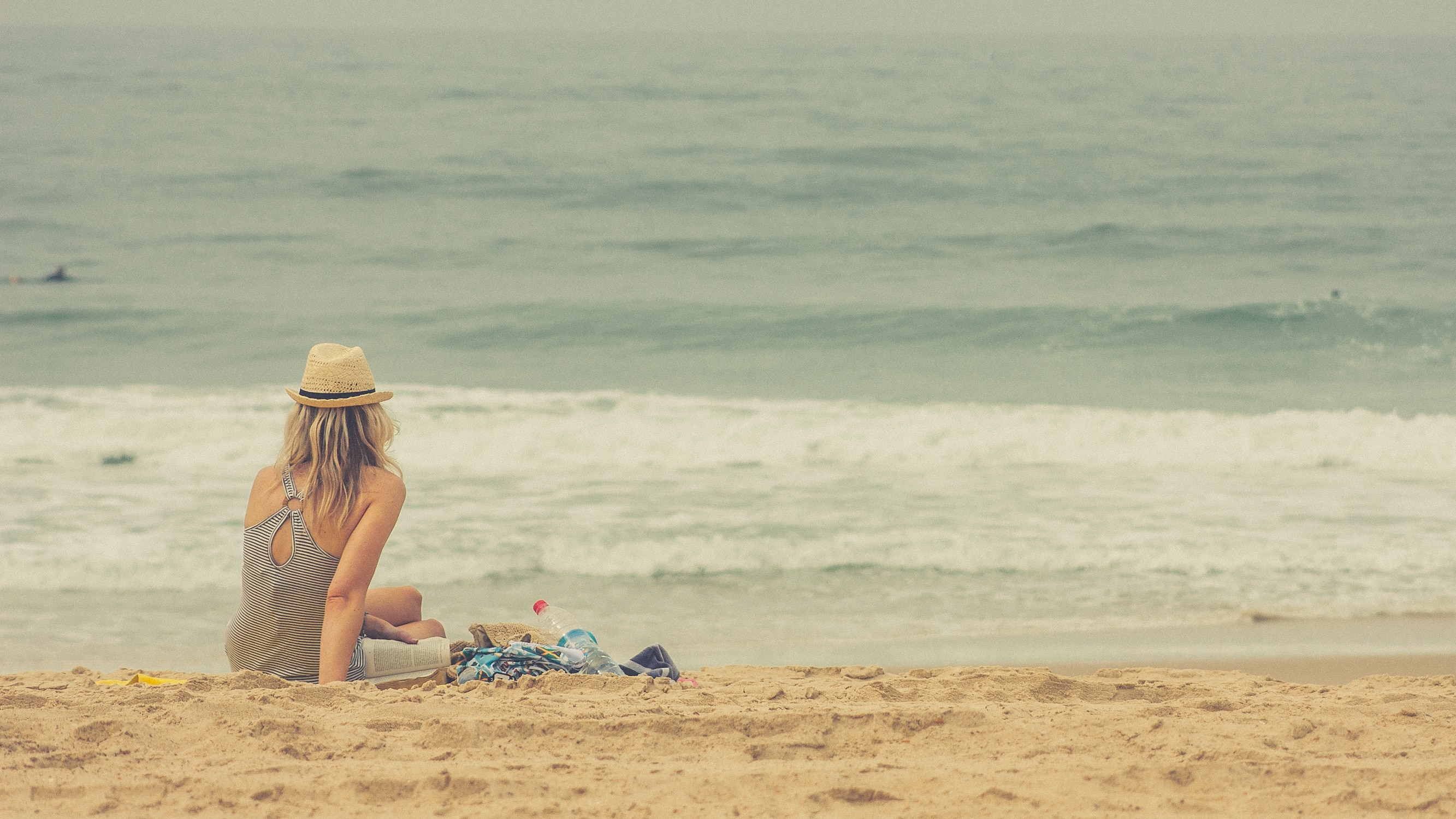 woman wearing hat and tank top sitting in beach