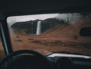 black steering wheel in front of waterfalls thumbnail