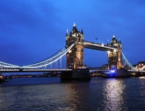 beige and black lighted bridge under dark-blue sky thumbnail