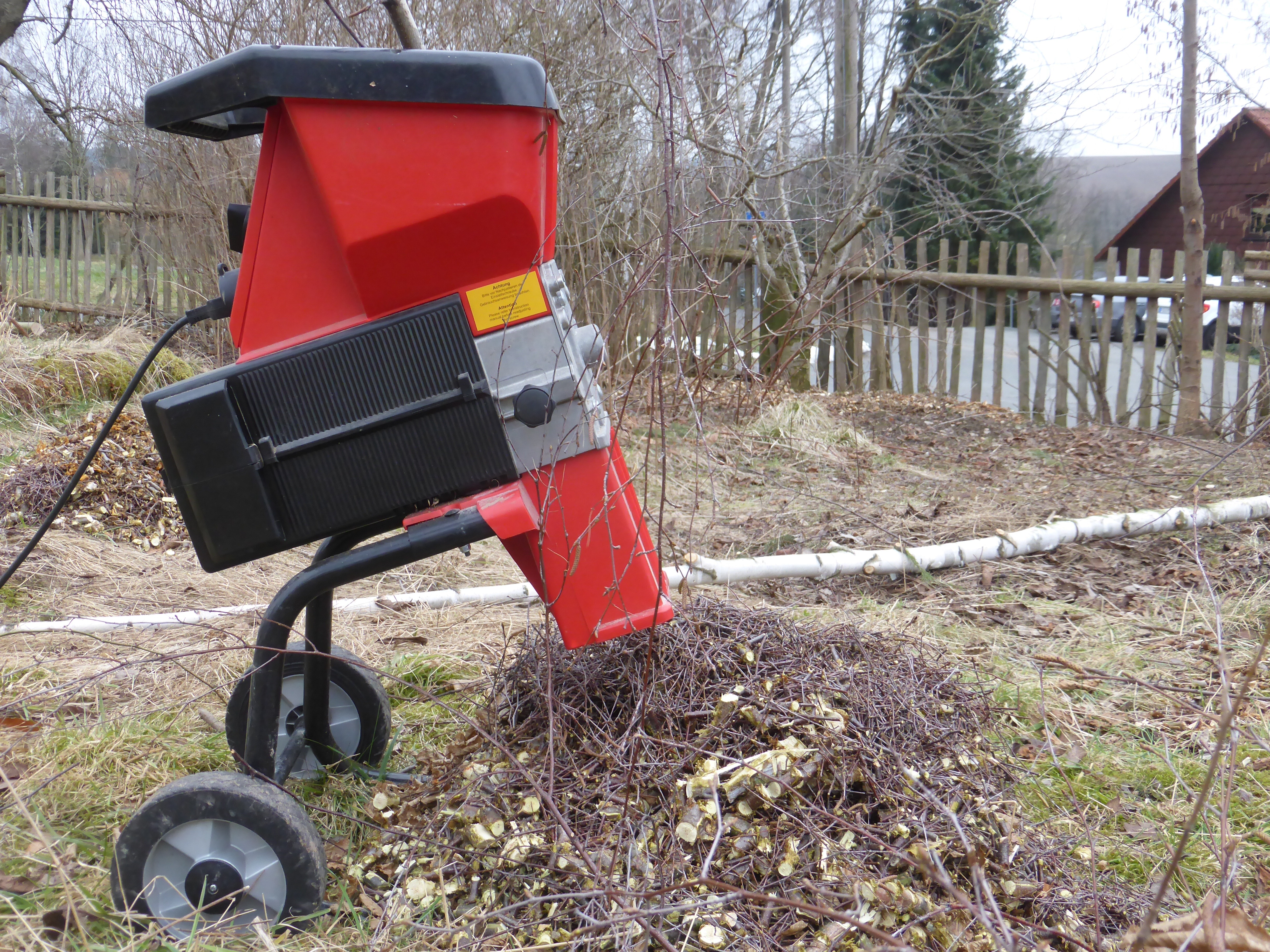red and black corded machine near wooden fence during daytime
