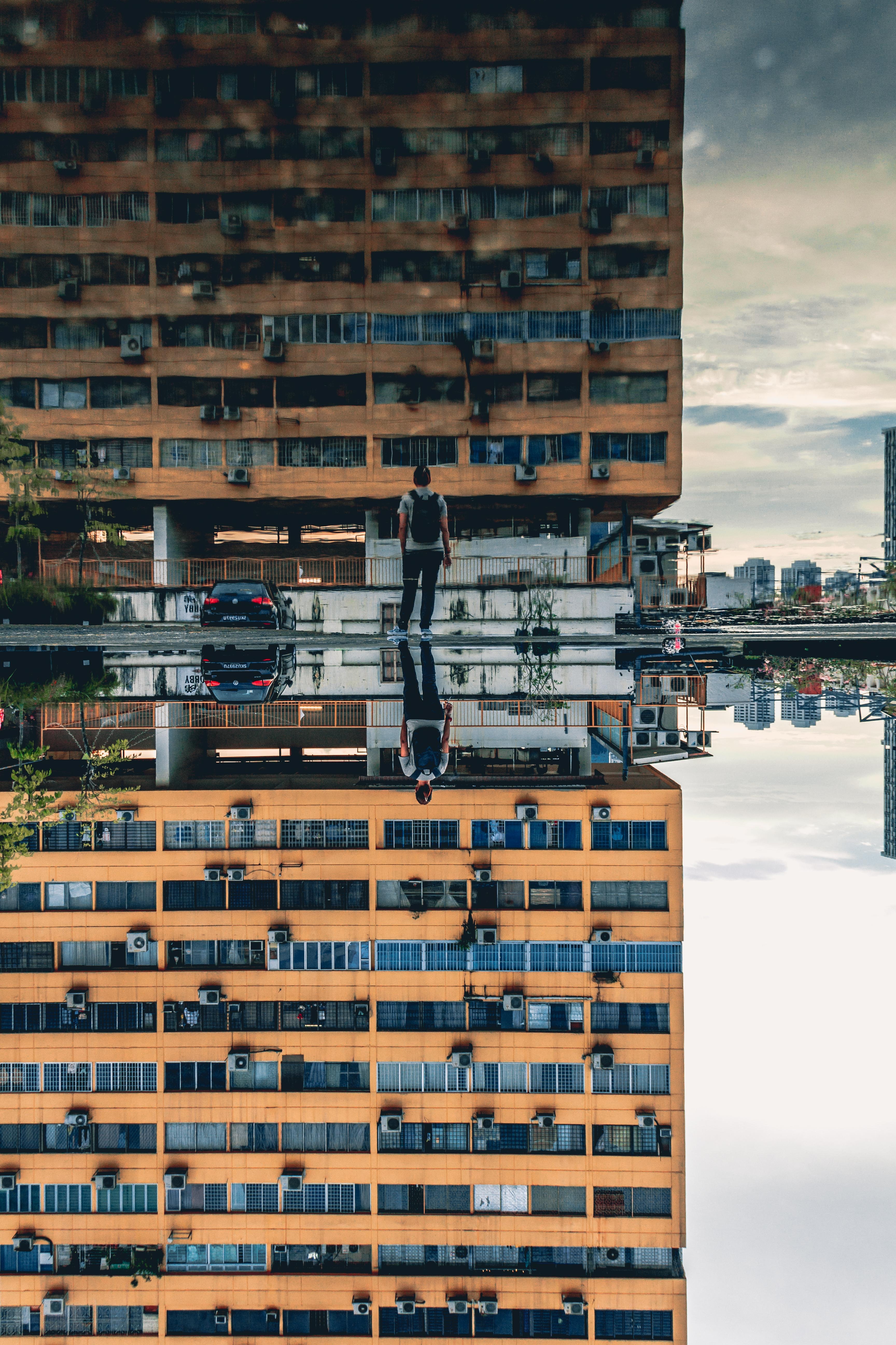 photo reflection of man and building during daytime photography