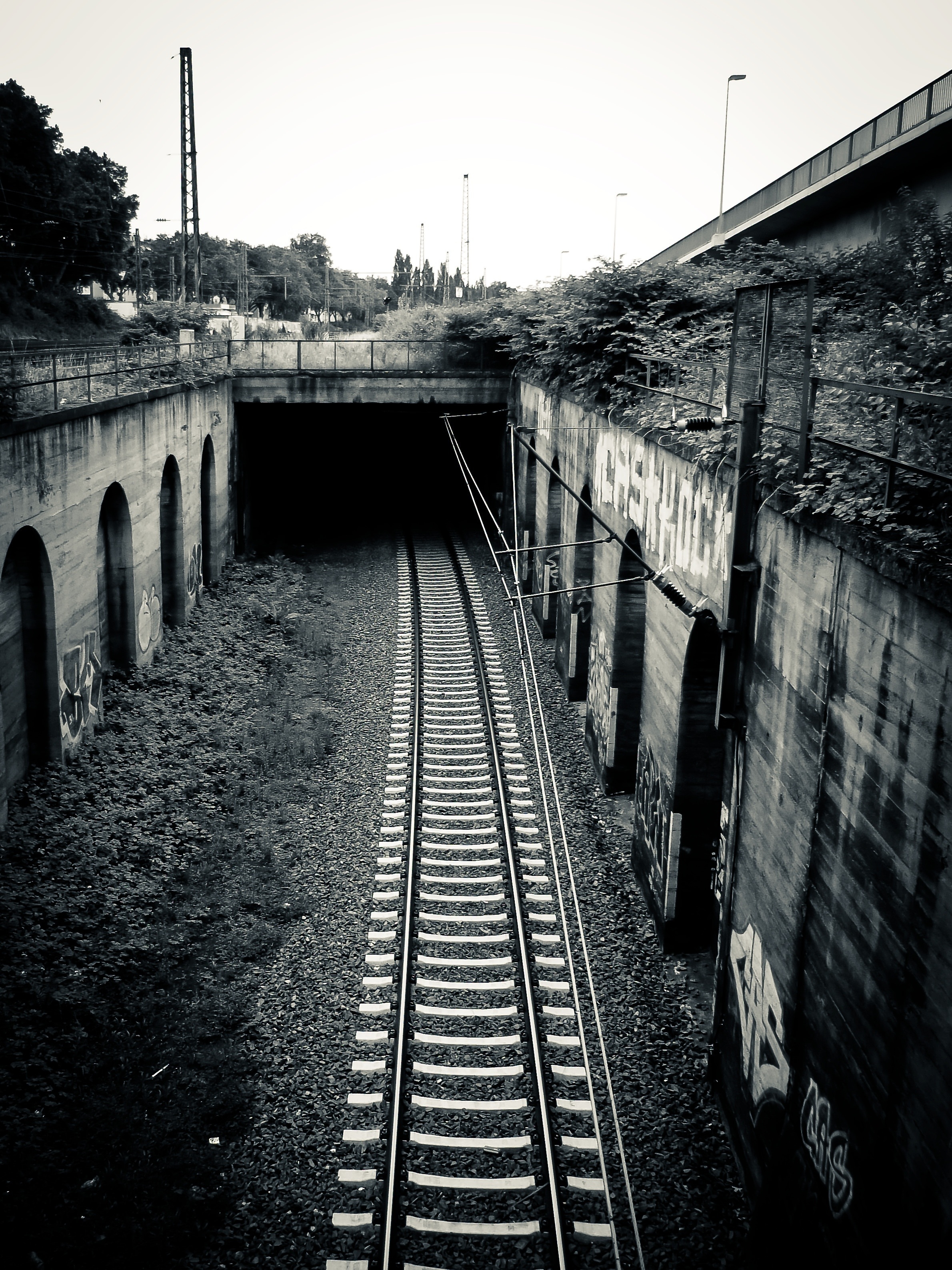 grey scale photo of tunnel railroad